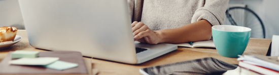cropped view of computer and person sitting behind desk typing